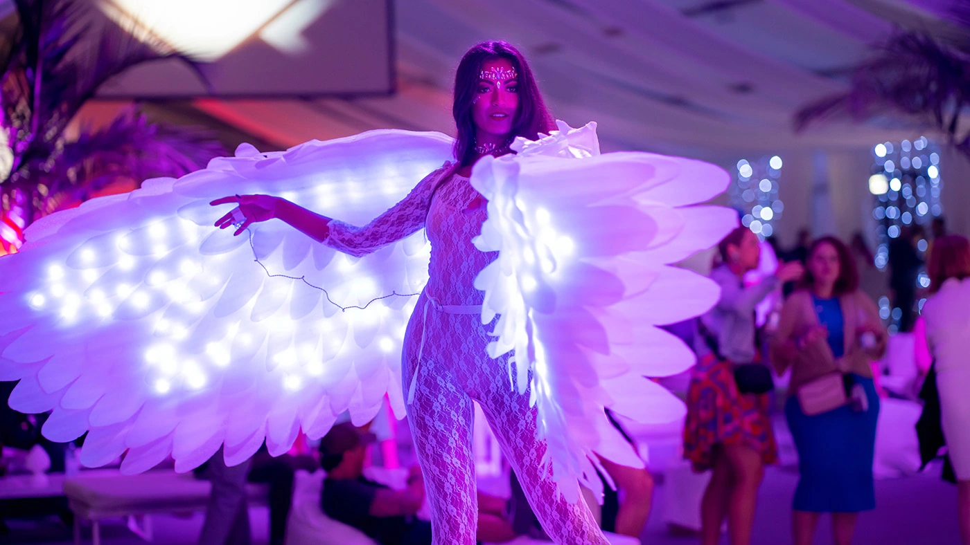 Ragazza travestita con ali a LED durante una festa a tema "White Party"